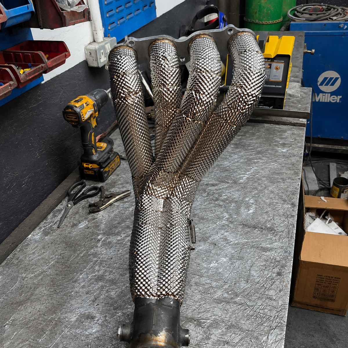 Four-branch exhaust manifold covered with a custom fabricated embossed stainless heat shield