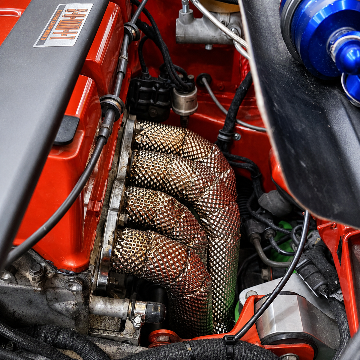 Embossed stainless heat shielding installed around an exhaust manifold in a honda civic ek k-swap engine bay